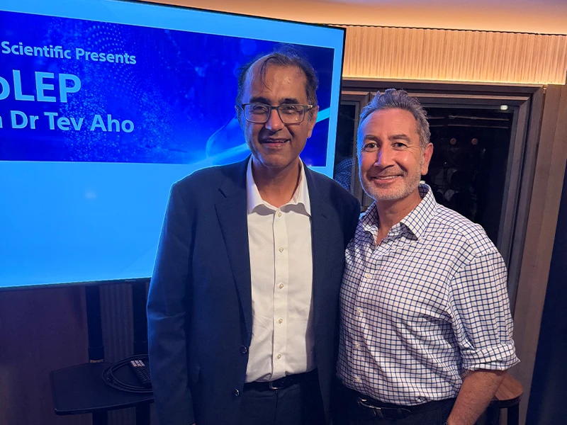 Dr Raji Kooner with Dr Tev Aho beside a HoLEP laser prostate surgery presentation slide, May 2026