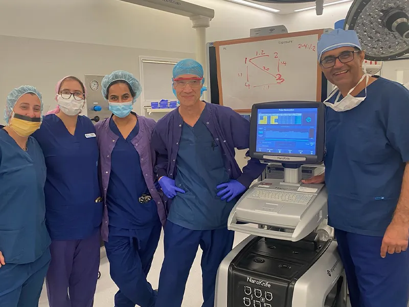 Operating-theatre team standing beside the NanoKnife pulse generator after a focal-therapy case, with Dr Raji Kooner at right