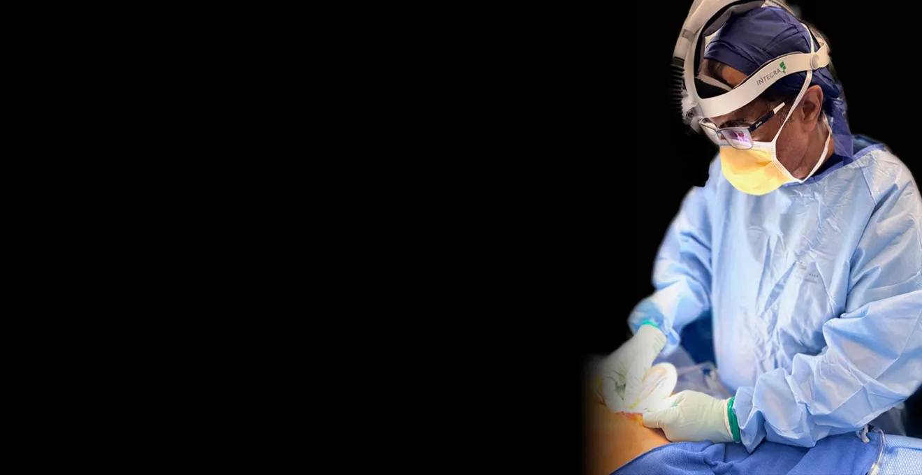 Dr Raji Kooner operating in theatre, wearing surgical gown, mask and headlight